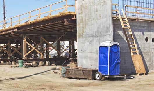 a clean and organized line of portable restrooms at a construction site, keeping workers content